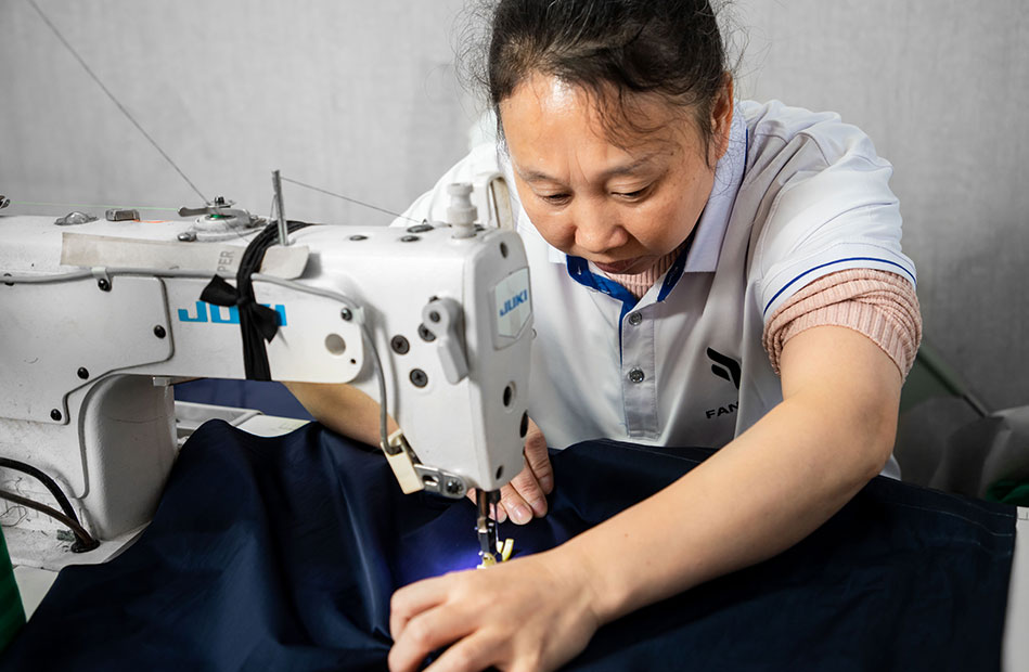 An skilled woman worker is sewing jackets
