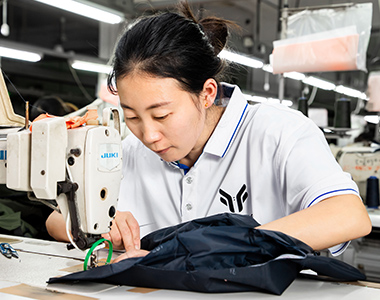 A skilled woman worker is sewing a jacket