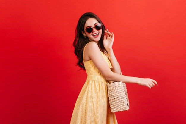 dark-haired girl wearing yellow dress with straw bag